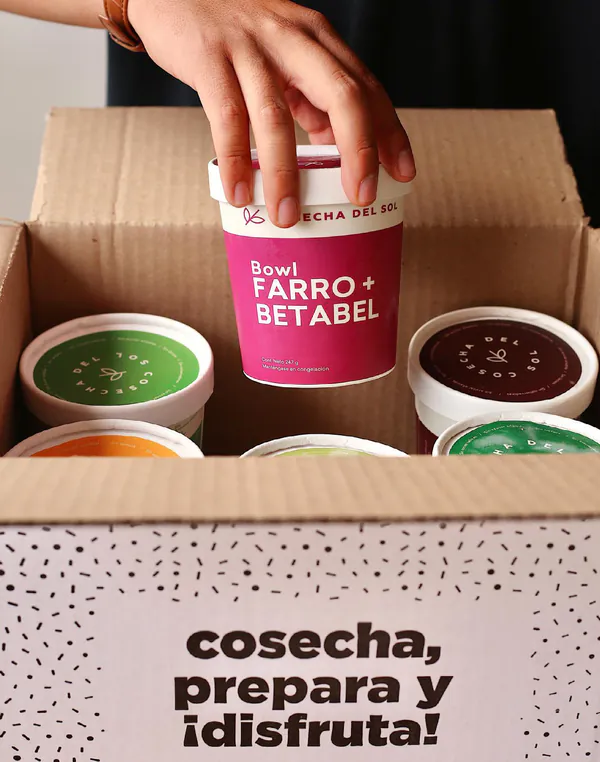 Mano que saca un empaque de una caja con la frase “cosecha, prepara y ¡disfruta!”.