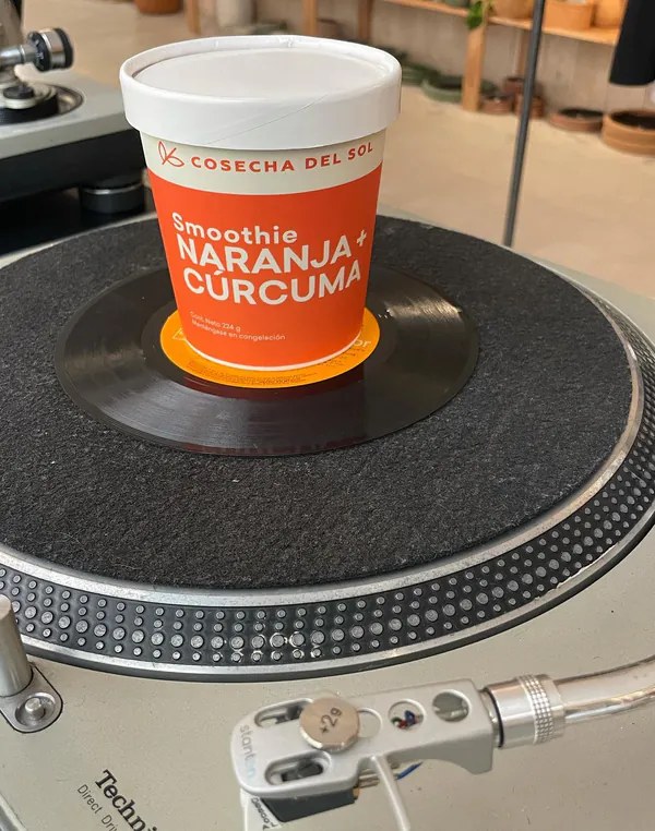 Empaque de smoothie Naranja + Cúrcuma encima de un disco, en una tornamesa.