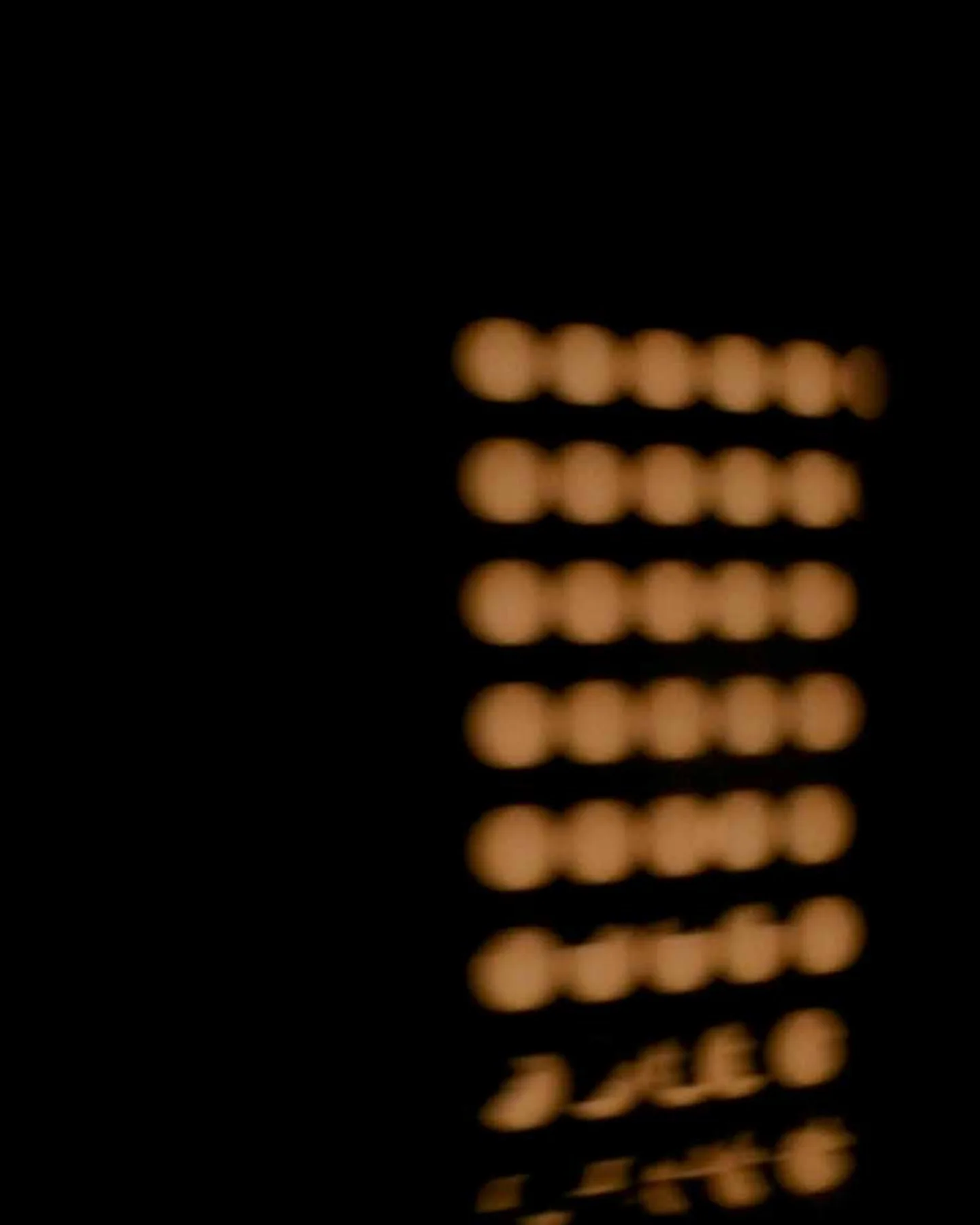 Hileras de luces ámbar desenfocadas sobre negro.
