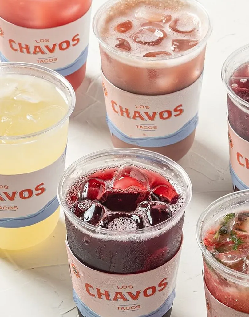 Vasos con bebidas de varios colores, cada uno con la faja del logotipo.
