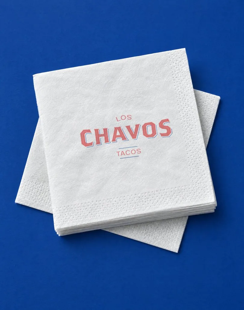 Mockup de servilletas blancas con el logotipo de Los Chavos en rojo, sobre fondo azul rey.
